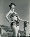 Ann Miller models a fashionable two piece bathing suit crafted by Gantner & Mattern of San Francisco. The venue is the outdoor studio of sculptress Cornelia Runyon who resided at the time on the cliffs overlooking the Malibu coastline in the Zuma Tract. Ann Miller worked three films in the mid-'40's for Columbia Studios, and Ned Scott photographed her often. This photograph was taken at the time of Director Arthur Dreifus' musical comedy, "Eadie Was a Lady", 1945