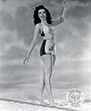Sporting a two piece swim suit, Columbia Studios dancer Ann Miller takes a stroll along a studio beach for Ned Scott’s camera. This photograph was used to support her role for the romantic comedy, "Eadie Was A Lady”, 1945, directed by Arthur Dreifuss.