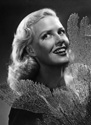 While Janis Carter was filming for Columbia Studios' hit adventure comedy 'A Thousand and One Nights'(1945), Ned Scott invited her to his home in La Canada for a photo session. This compelling image is one of several to emerge from that effort. Janis is holding as a prop a sprig of black coral which Ned Scott kept prominently displayed for dramatic contrast over his white brick mantel piece.