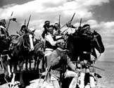 Impersonating Geronimo and his warriors, a group of local Navajo tribesman, recruited by Walter Wanger Productions for the film, gather on a bluff preparing to attach the pasengers traveling in the stagecaoch below.