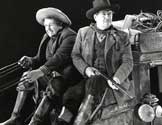 Stagecoach movie: The 1939 caption attached to this print reads: Buck, (Andy Devine), the stage driver, is pleased with the swift trotting of his six-horse team because he thinks the coach is headed for the protection of a troop of cavalry. Curly (George Bancroft), the U.S. Marshall with shotgun at the ready, doesn't share Buck's anticipation as he anxiously scans the horizon for attacking Apaches in Walter Wanger's "Stagecoach". 