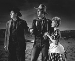 Ringo (John Wayne), Marshall Wilcox (George Bancroft) and Dallas (Claire Trevor) gaze at something in the hills surrounding the Apache Wells relay station. Ringo, while trying to escape from the Marshall who is still inside the relay station, stops abruptly, dismounts from the station owner's horse that has run back to the station, while Marshall Curly and Dallas who are trying to stop him, catch up. Off in the distance Apache warriors are signalling with smoke plumes, announcing their threatening presence. Director John Ford's epic saga of the frontier, Stagecoach, 1939.