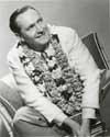 Fredric March photos: Studio caption for this photograph reads: "Fredric March is adorned with some beautiful flower leis in an Hawaiian sequence in "Trade Winds", the new Walter Wanger picture in which he co-stars with Joan Bennett. In the story March, amorous private detective, goes to Honolulu in search of Miss Bennett, a suspected murderess, beginning a humorously exciting chase that eventually leads half way around the world." A portrait of Fredric March supporting his role in Director Tay Garnett's lighthearted murder mystery, "Trade Winds", 1938.