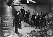 .Busted! Emil the Bewer, played by Gene Lockhart (hatless with buttonniere) finds himself in a dangerous position while surrounded by members of the Gastapo in the basement of one of his buildings in Prague. Suspected by the Gestapo of the criminal act of assasination, Emil maintains that he is innocent. It turns out, however, that the pile of coal hides the body of Gestapo Inspector Gruber who was recently murdered by Czech resistance fighters. Emil does not know that he is the victim of a well-planned plot by Czeck resistance to discredit him. Director Fritz Lang's film noir wartime thriller "Hangmen Also Die", 1943.