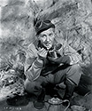 Burgess Meredith, as Ernie Pyle, enjoys a bite of C rations on the set of The Story of G.I. Joe. Ernie often heated his rations by using gasoline. He would dig a little hole in the dirt or sand, place some gas into the hole, cover it again with sand, and light it. The gas would burn slowly enough for him to heat a can of food or a cup of coffee. Ernie preferred the British COMPO rations to the U.S. Army C rations because there was more variety. Many G.I.'s, right after landing in Oran (where Ernie came ashore during Operation Torch) would give away portions of their C rations to ragged Arab children who followed the G.I.'s around relentlessly.