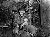 Camp dogs were everything to the combat soldier at the front. Here Burgess Meredith plays Ernie Pyle in The Story of G.I. Joe holding the camp's mascot dog during a rainy and cold moment at the front. Burgess Meredith was already serving in the U.S. Army on active duty as a Captain when Lester Cowan approached him to take the role of Ernie Pyle. The Army released Meredith on an honorable discharge so he could take the role, but that occurred only after presidential adviser Harry Hopkins greased the way and George C. Marshall approved the discharge personally.