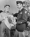 Burgess Meredith, the actor who portrays Ernie Pyle, admires a captured Japanese ceremonial item from the Battle of Leyte which is presented by an officer from the 11th Airborne Division. This scene occurred in Southern California during filming of director William Wellman’s wartime drama, “The Story of G.I. Joe”, 1945.