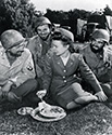 Cadet Nurse Beulah Tyler shares a bite with combat veterans from the 34th Division on the set of The Story of G.I. Joe. From left to right are Cpl. Chester (Pappy) Nowlen, Pvt. Charles Rozell and Pvt. Fred Ross. Because special dispensation was provided to these combat vets for their participation in the film, the War Department allowed them to grow beards if they wished. During actual combat in North Africa, that was the case, anyway. Director Wellman cheered this fact because, as he put it, I want to make this the goddamndedest most honest picture that has ever been made about the doughfoot.