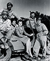 Cadet Nurse Beulah Tyler loosens up with combat veterans of the First Division on the set of The Story of G.I. Joe. From left to right are seated Corporal Chester (Pappy) Nowlen, Pvt. Fred Ross , Sgt. Charles Rozell, Pvt. Jim Cosso and Nurse Lt. Red Murphy.