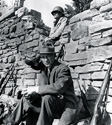 Ernie Pyle and one of the soldiers relax between filming of the movie. Surrounding Ernie are authentic weapons and battle gear from the film production.