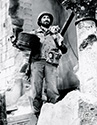 Sgt. Warniki, played by Freddy Steele, emerges from a domicile in a captured town in Italy with a phonograph, an item he has been looking for ever since his stateside wife sent him a recording with his toddler son's voice. Scene from Director William Wellman's wartime authentic wartime drama, "The Story of G.I. Joe", 1945.