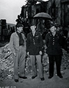 George Lait, U.S. War Correspondent with the International News Service, chats with officers on the set of The Story of G.I. Joe while the film crew in the background prepares for a scene. George Lait was present on the set along with eight other correspondents at the suggestion of Ernie Pyle. These men all played themselves in various scenes in the film. Next to Lait are combat veterans Col. J.G. McGammon and Lt. Col. Henry. Both officers served with distinction under General Joe Stillwell on the CBI front (China-Burma-India).