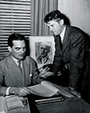Lee Miller, seated, and Paige Cavanaugh, longtime friends of Ernie Pyle from the earlier days in news service, review and discuss the script for The Story of G.I. Joe. Both had been hired by Lester Cowan as consultants. They helped tune the script with Ernie Pyle. A portrait of Ernie looms behind them as they work.