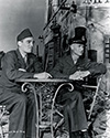 Lee G. Miller, former editor of the Washington Daily News and Ernie Pyle relax on the set of The Story of G.I. Joe as they observe filming in progress. Lee Miller and Ernie had been friends for many years in the news business. Both Miller and Paige Cavanaugh, another of Ernie's close news buddies joined Ernie on the set of the film as paid consultants. Producer Lester Cowan no doubt agreed to this idea which most likely emerged in the many discussions surrounding the final tweaking of the movie script.