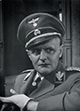 J.J. Twardowski portrays Reinhold Heidrich, the vicious anti-semite and brutal murderer of several million Jews during the course of WWII in Fritz Lang's Hangmen Also Die, 1943. He appears in the beginning of the film, dominating the scene with his glowering presence and setting the tone for the struggles to come as the plot unfolds.